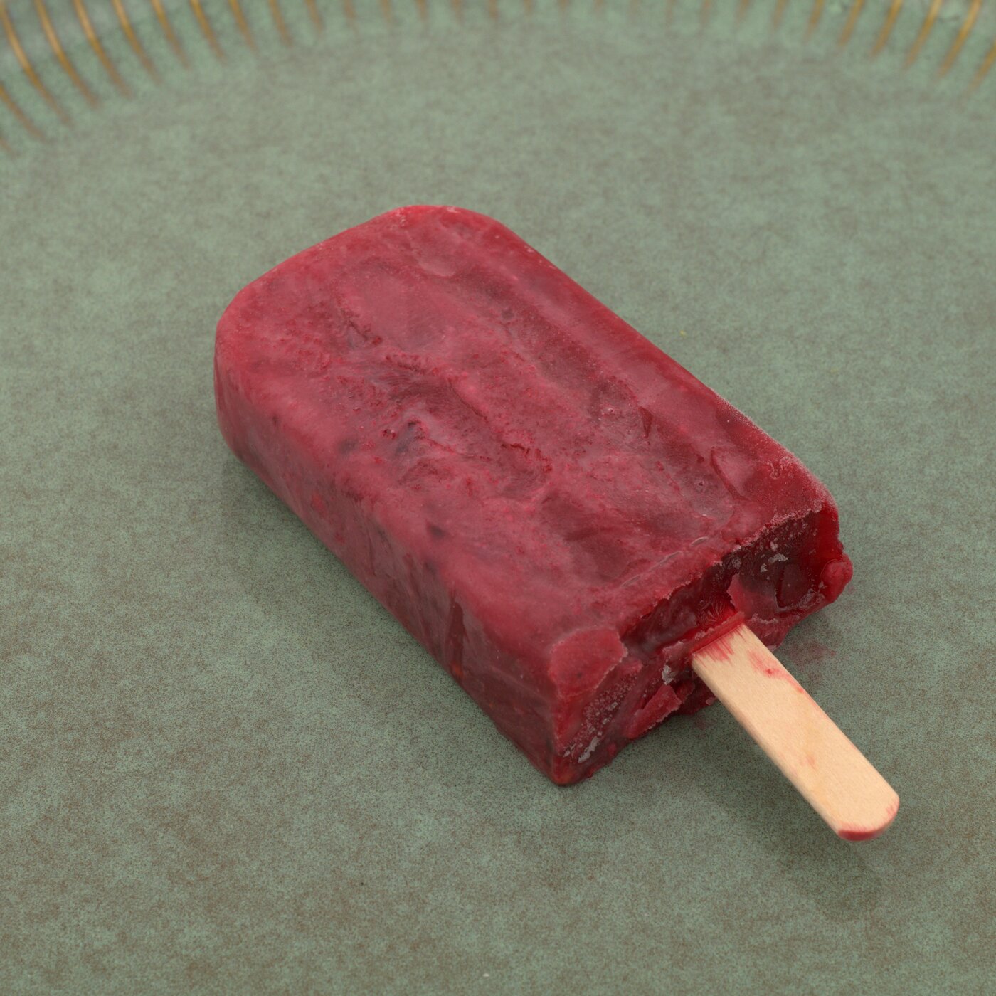 Red Bastani Lavashaki mixed-berry ice lolly on a green ceramic plate